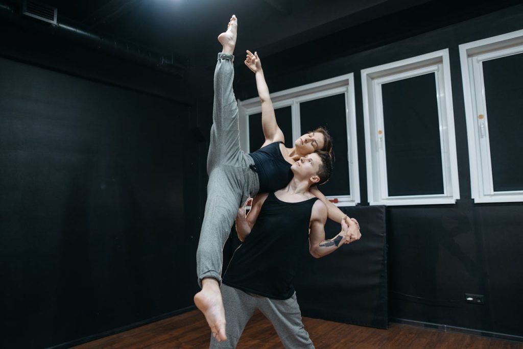 A man and woman practice contemporary dance moves in a studio, showcasing flexibility and strength.